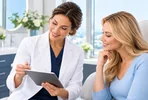 Doctor reviewing consultation details with a patient on a tablet.